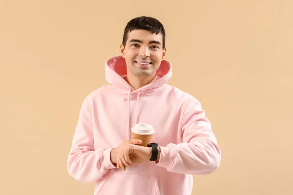 Young Man Hoodie Coffee Looking Watch Beige Background — Stock Photo, Image