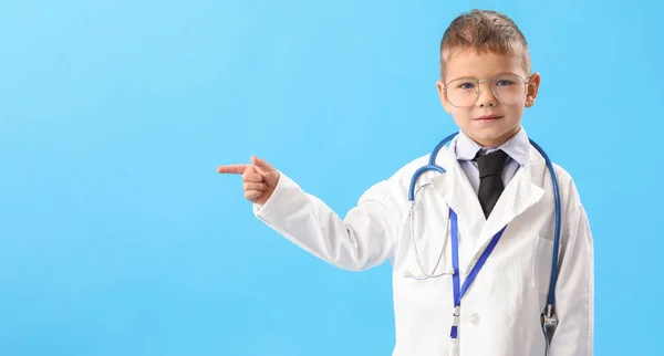 Netter Kleiner Arzt Zeigt Auf Etwas Auf Blauem Hintergrund — Stockfoto