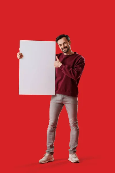 Przystojny Mężczyzna Wielkim Pustym Plakatem Pokazującym Kciuk Góry Czerwonym Tle — Zdjęcie stockowe
