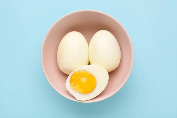 stock image Bowl with delicious boiled eggs on blue background