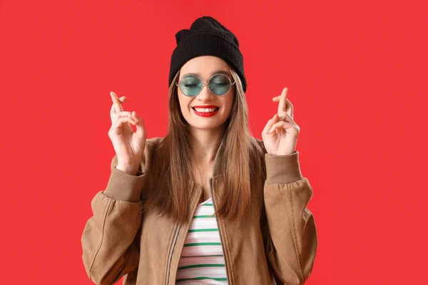 Stylish Young Woman Crossing Fingers Red Background — Stock Photo, Image