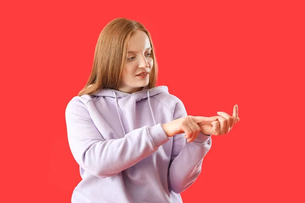 Beautiful redhead woman in hoodie counting on red background