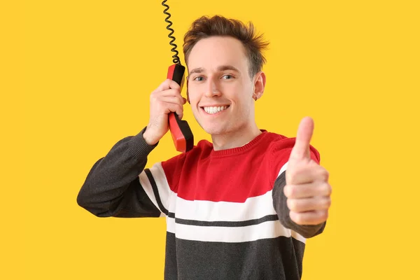 酷酷的年轻人 有电话接收器 黄色背景显示大拇指向上 — 图库照片