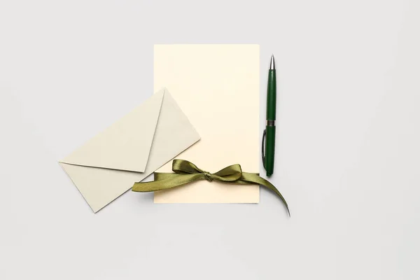 Composition with blank card, envelope and pen on white background