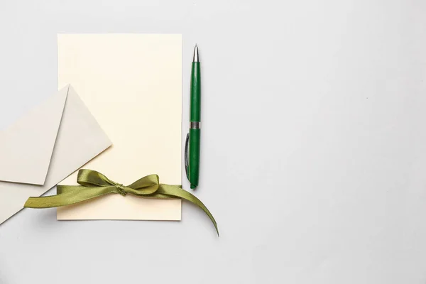Composition with blank card, envelope and pen on white background
