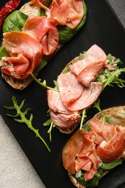 Lezzetli bruschetta tabağı, arka planda jambon, yakın plan.