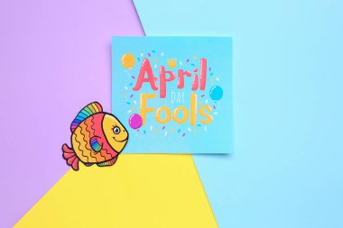 Metni APRIL FOOLS Day olan kağıt ve renk arkaplan üzerinde balık