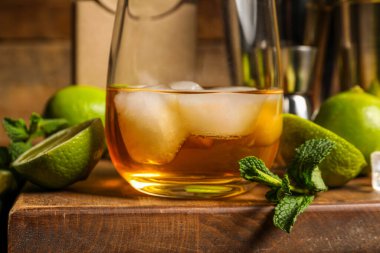 Bir bardak buzlu rom, nane ve kireç ahşap masada, yakın plan.