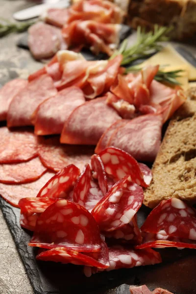 stock image Slate plate with assortment of tasty deli meat on table, closeup