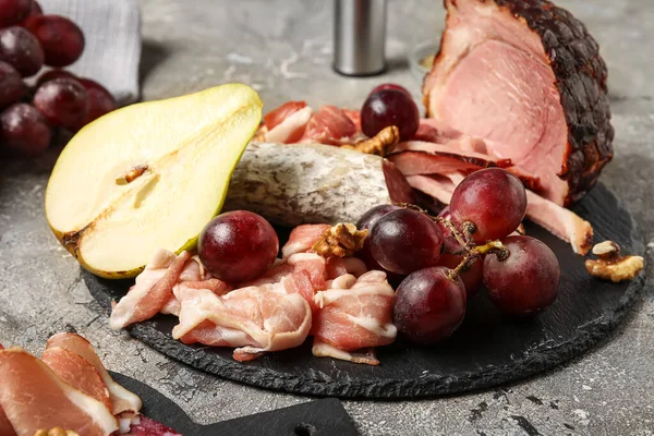 stock image Slate plate with assortment of tasty deli meats on grey background