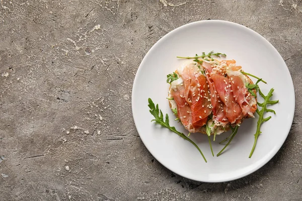 stock image Plate of tasty bruschettas with ham on grunge background