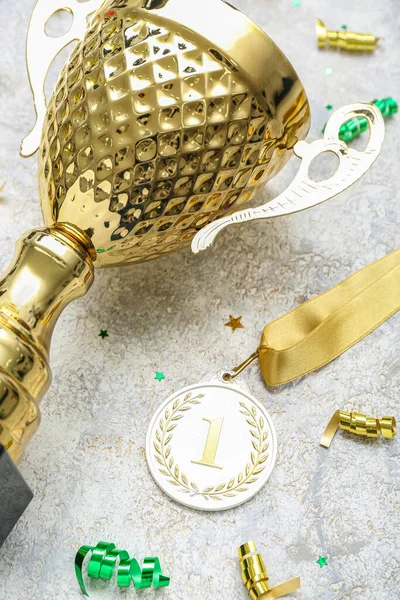 Gold cup with first place medal and serpentine on grunge background, closeup