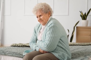 Apandisiti olan yaşlı bir kadın yatak odasında oturuyor.