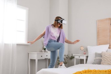 Pretty young woman in VR glasses in bedroom