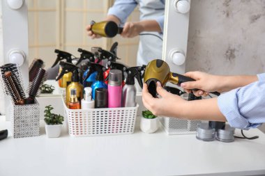 Güzellik salonundaki masasında saç kurutma makinesi olan kuaför, yakın plan.