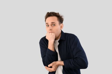 Scared young man on light background