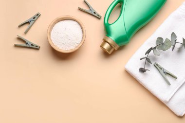 Çamaşır deterjanı, mandallar ve bej arka planda okaliptüs dalı.