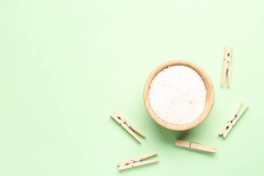 Yeşil arkaplanda çamaşır deterjanı ve mandallar