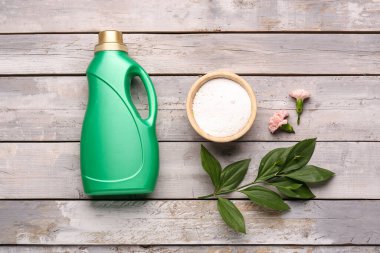 Çamaşır deterjanları, karanfil çiçekleri ve ahşap arka planda bitki dalı.