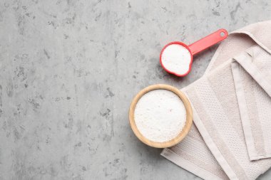 Çamaşır deterjanı ve gri arkaplanda havlu.