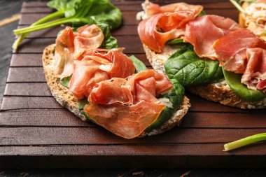 Koyu ahşap arka planda jambonlu lezzetli bruschettalar, yakın plan.