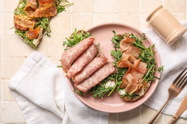 Pastırma, jambon ve arkaplanda roka olan jambon bruschetalar.