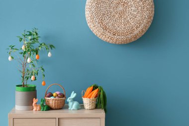 Mavi duvarın yanındaki ahşap dolapta Paskalya süslemeleri.