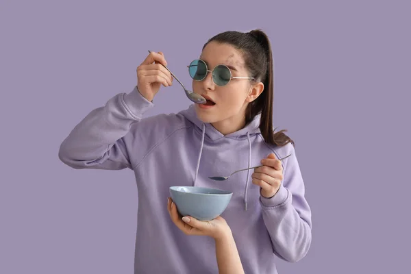 Młoda Kobieta Łyżką Jedząca Śniadanie Liliowym Tle — Zdjęcie stockowe