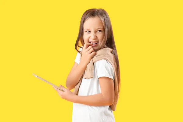 Little Girl Tablet Computer Biting Nails Yellow Background — Zdjęcie stockowe