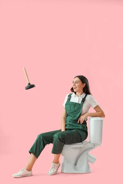 Female Plumber Sitting Toilet Bowl Flying Plunger Pink Background — Stock Photo, Image