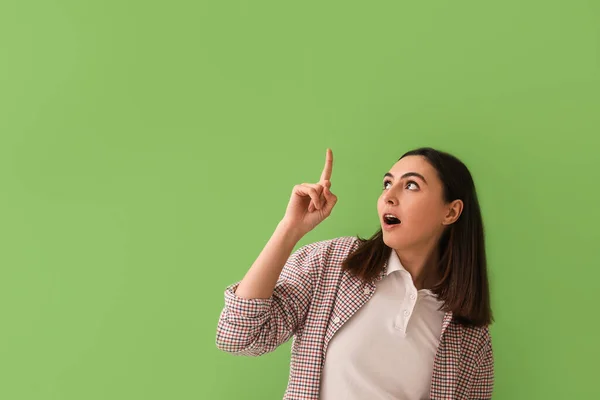 Zszokowana Młoda Kobieta Wskazująca Coś Zielonym Tle — Zdjęcie stockowe
