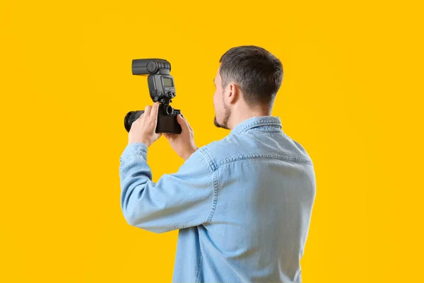 带黄色背景专业相机的男性摄影师 — 图库照片