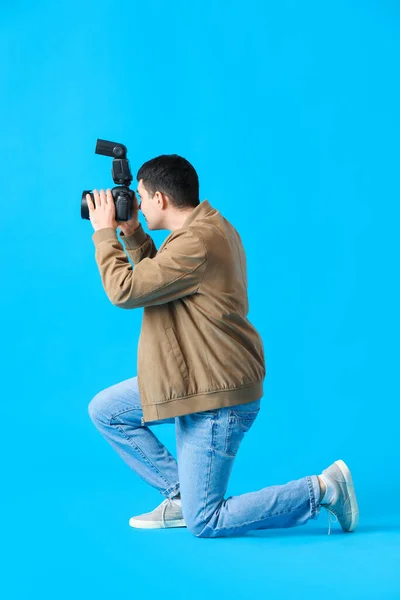 青の背景にプロのカメラを持つ若い男性写真家 — ストック写真