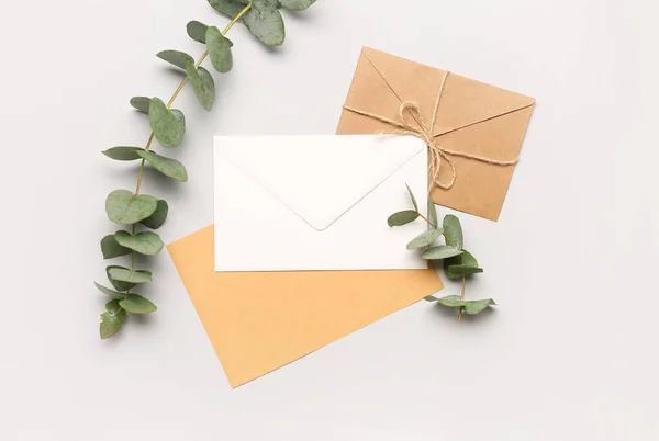 Composition with envelopes, card and eucalyptus branches on white background