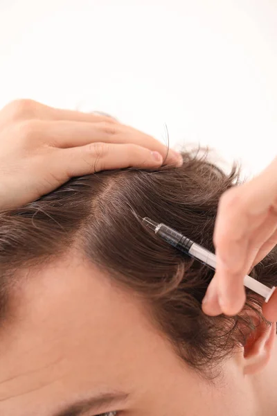 Young man with hair loss problem making injection in bathroom, closeup