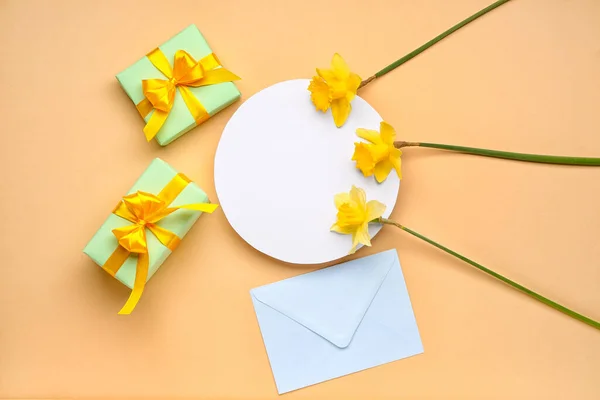 Beautiful narcissus, envelope, gift boxes and round blank card on color background