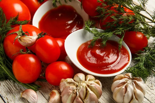 stock image Bowl with tasty ketchup and fresh vegetables on light wooden background, closeup