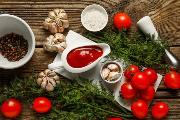 stock image Gravy boat with tasty ketchup and fresh vegetables on wooden background