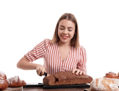 Kadın fırıncı beyaz arka plandaki masada taze ekmek kesiyor.