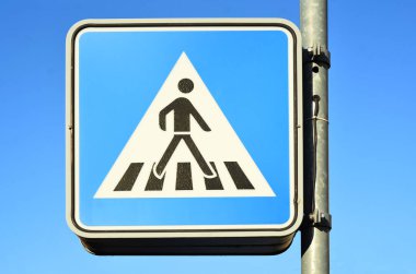 Pedestrian crossing sign against blue sky, closeup