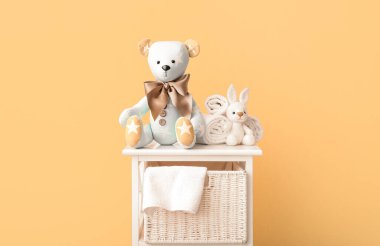 Oyuncak ayı ve tavşan. Bej duvarın yanında raflarda havlular var.
