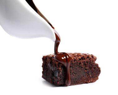 Beyaz arka planda lezzetli çikolatalı brownie parçasının üstüne dökülüyor.