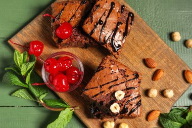 Tahtada yeşil ahşap arka planda lezzetli çikolatalı brownie parçaları var.