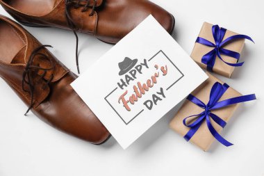 Mutlu Babalar Günü yazılı kart, şık erkek ayakkabıları ve beyaz arka planda hediyeler.