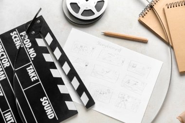 Çizim tahtası, not defteri ve ışık arkaplanı üzerine film makarası ile alkış.