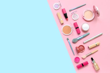 Mavi ve pembe arkaplanda makyaj fırçaları ile dekoratif kozmetik ürünler