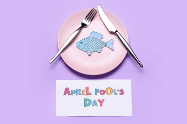 Kağıtlar APRIL FOOL 'S Day, eflatun arkaplan üzerine balık ve masa ayarı