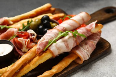 Lezzetli İtalyan Grissini ahşap tahtası, arka planda domuz pastırması, yakın plan.