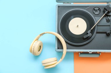 Renk arkaplanında vinil diski ve kulaklığı olan kayıt çalar