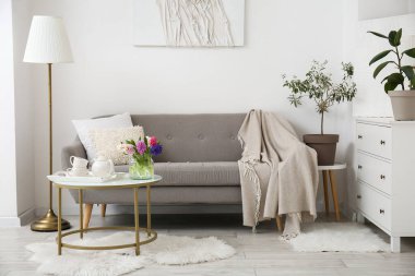 Rahat kanepesi, sehpası ve lambası olan modern oturma odasının içinde.